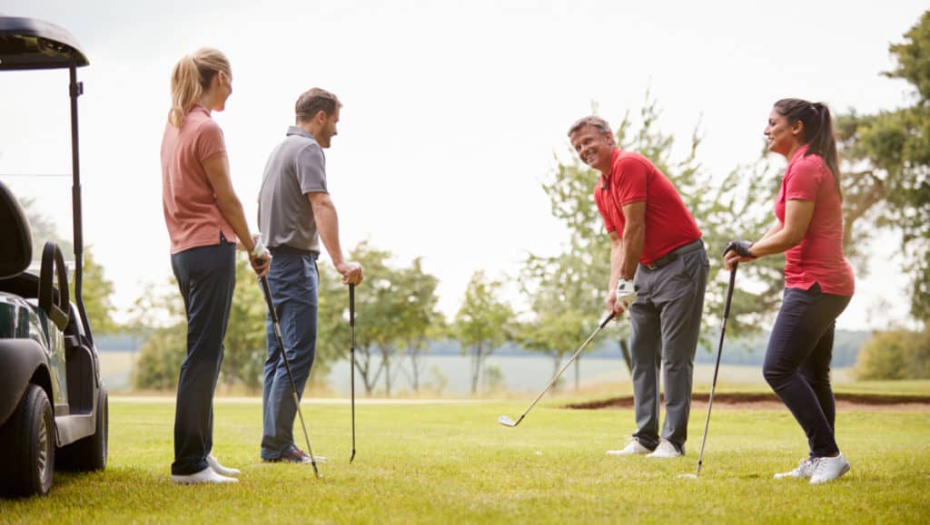 Golf Professional Demonstrating Shot On Fairway To Group Of Golfers During Lesson