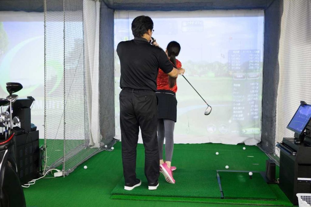 woman hitting golf ball with launch monitor