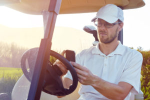 man in golf cart looking at phone