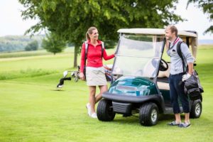 golfers carrying golf bags next to a golf cart