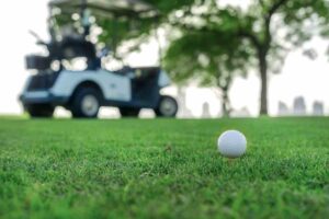golf ball sitting on tee in front of golf cart