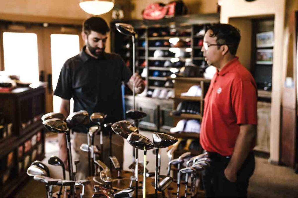 two men looking at golf clubs in a golf store
